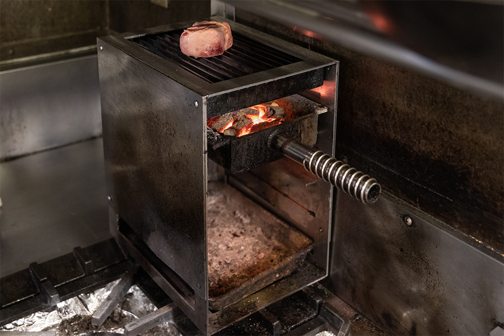 22.5×30×35cm、コンロひと口サイズのポータブル薪火グリル。把手の付いたトレイに熾火を入れて差し込む。差し込む位置が４段あって、段を変えることで、火力の調整ができるスグレモノ。