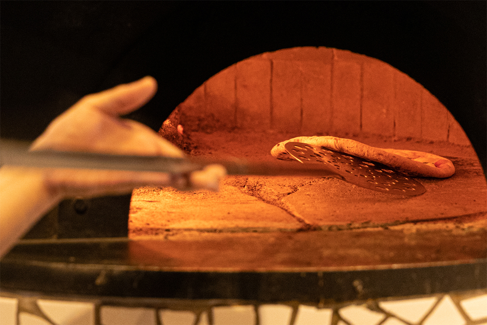 炉床の温度は場所によって異なり、当然、奥のほうが熱い。状況を見ながら、置く場所を判断する。生地裏までしっかり焼くのがドンブラボー流。