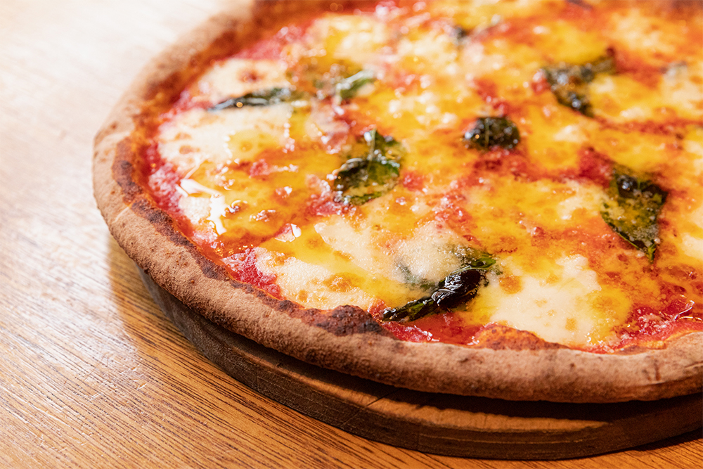 窯内の薪火の状態と温度を把握しておくことで、生地と食材への火入れをピタリと決める。