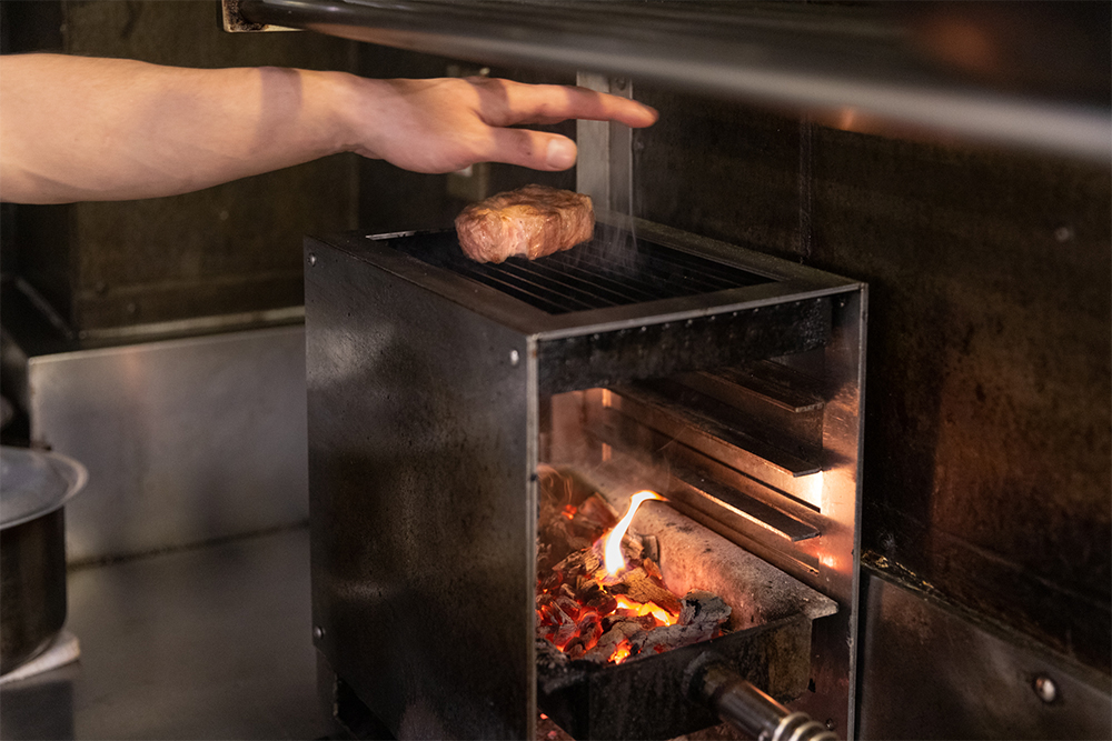 熾火を最下段に移して、遠火でじっくり焼き上げる。やわらかい熱が食材全体を包み込むので、食材にストレスがかからない。脂が落ちると煙が上がって薫香が付く。