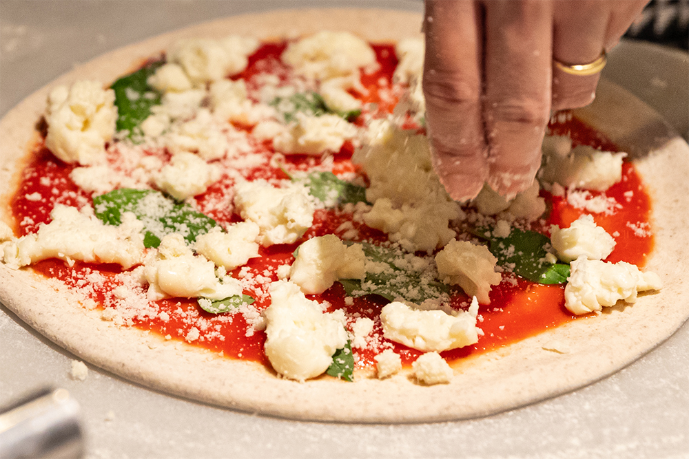 チーズ、トマトソース、オリーブオイルが混然一体となって乳化するような分量と配置を計算してのせる。