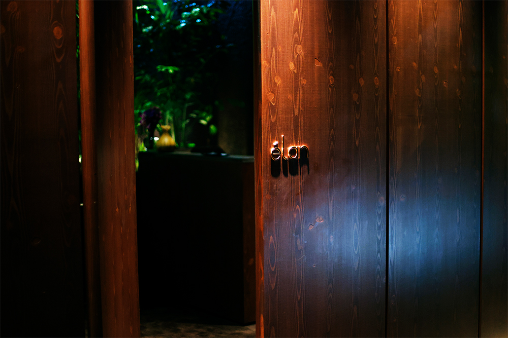 緑が生い茂る４階フロアの奥に、ひっそりと控えるエントランス。天井高いっぱいの大きな木の扉が、日常と非日常を分ける結界だ。ドアをゆっくりと押し開ける瞬間から、ときめきが始まっている。