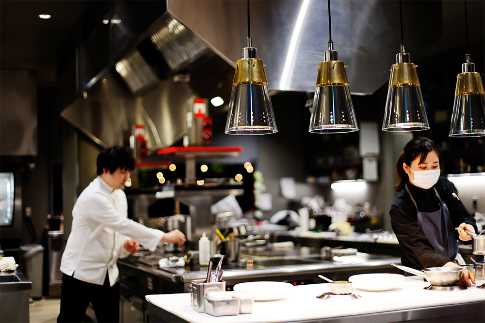 信太シェフ（左）自らが設計も担当したという「élan」の厨房。姉妹店のビストロ「bonélan（ボネラン）」の料理も、ここで調理する。