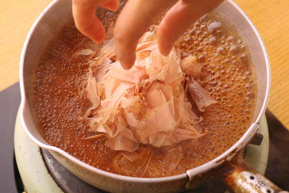 鍋が沸いたところに花がつおを落とし、火を止める。 [８]粗熱をとる