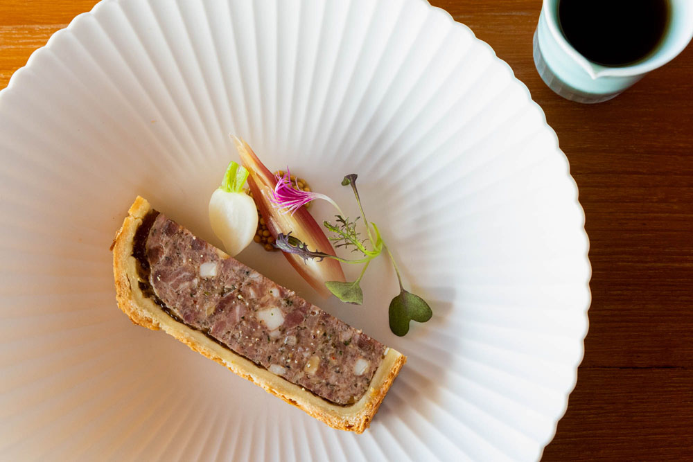 ２つの農場から取り寄せたアグー豚の部位を大胆に組み合わせ、特有の旨味の濃さ、上質な脂の甘味をふんだんに盛り込んだ「パテ・アン・クルート」。京丹後産のカブとミョウガを添え、軽やかさも感じられるアントレの仕立てに。豚と鴨からだしを取った滋味深いコンソメが添えられる。