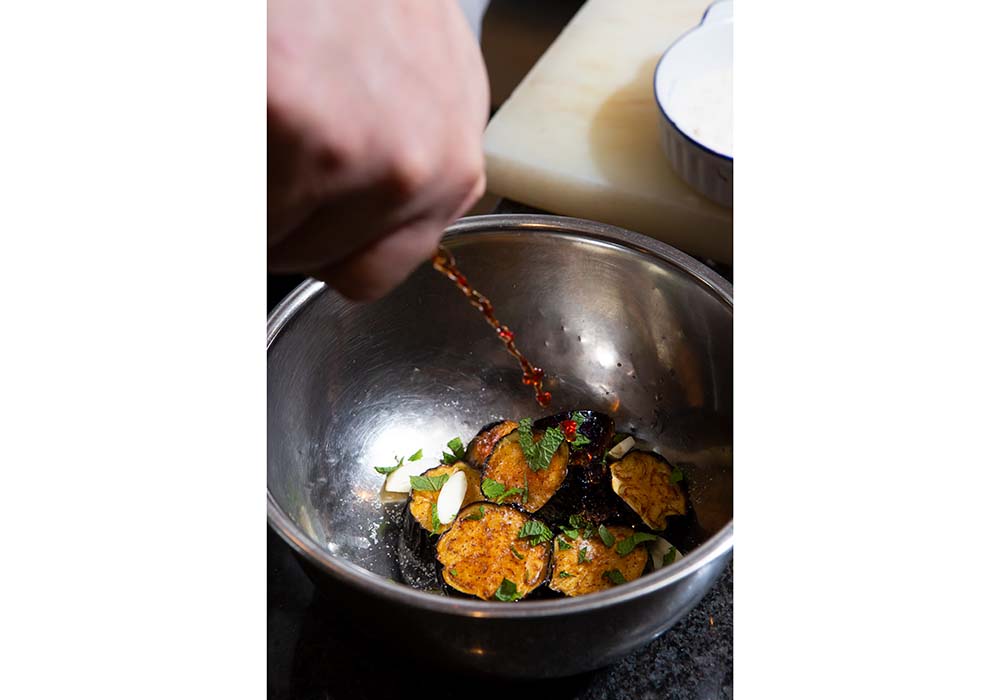 油を切って、ボウルに移す。塩ひとつまみ、ニンニク、ミント、赤ワインビネガーをふりかける。残りのナスも同じ手順を繰り返す。 POINT：塩、ニンニク、ミント、ビネガー。味が入ってほしい順に加える。 ［４］すべてを揚げたら熱い揚げ油（60ml）を、ニンニクをねらって注ぐ。常温になるまで冷ます。 ［５］皿に盛り、ミントの葉（分量外）を添える。