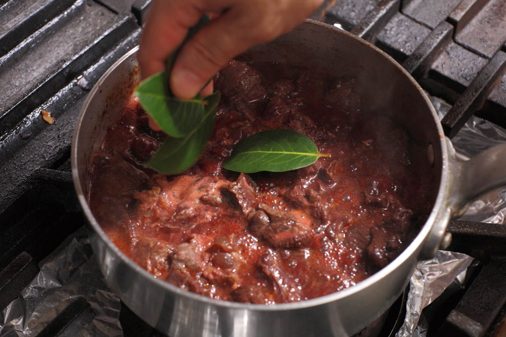 トマトピュレ、ローリエを加え、炒め合わせる。 [７]赤ワインを加える