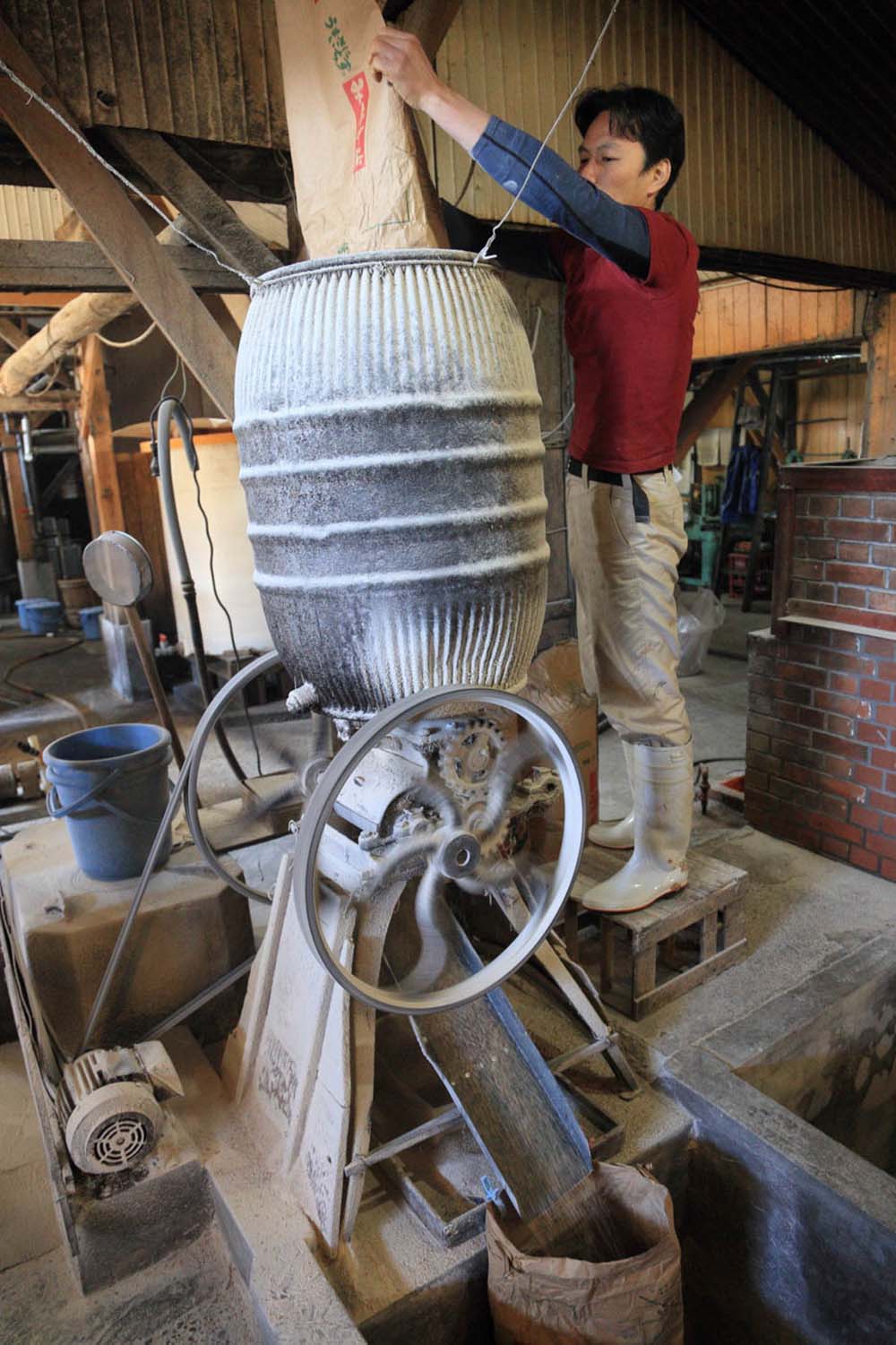 炒った小麦は、歯車がついた機械で細かく砕く。