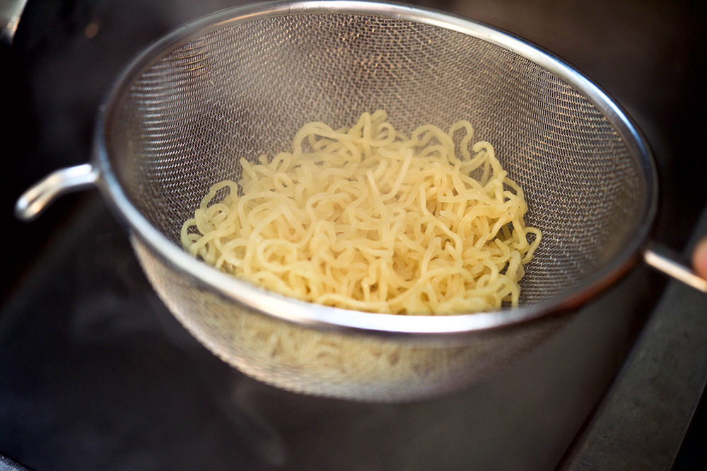 ザルで麺を湯切りする