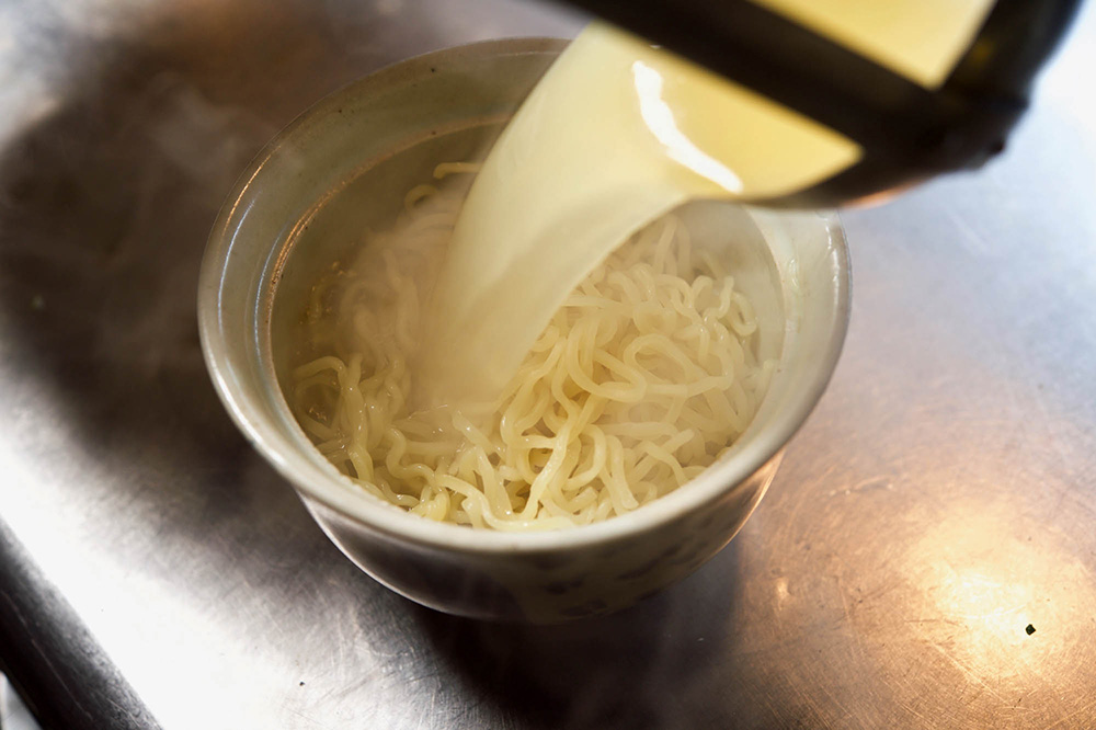 麺にスープを注ぐ