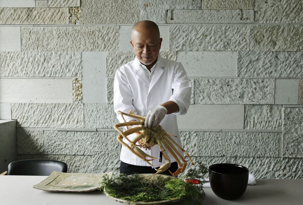 茹で上がったカニは宿泊客の目の前で豪快に手で割り、盛り上げてサーブ。脚を１本外すごとに、汁がしたたり、蟹の濃厚な香りが立ち上る。「あえて筋を入れるようにバキバキ折っていくのがコツ。カニの味噌が付着して、たまらない感じになるんです（笑）」と刀根さん。