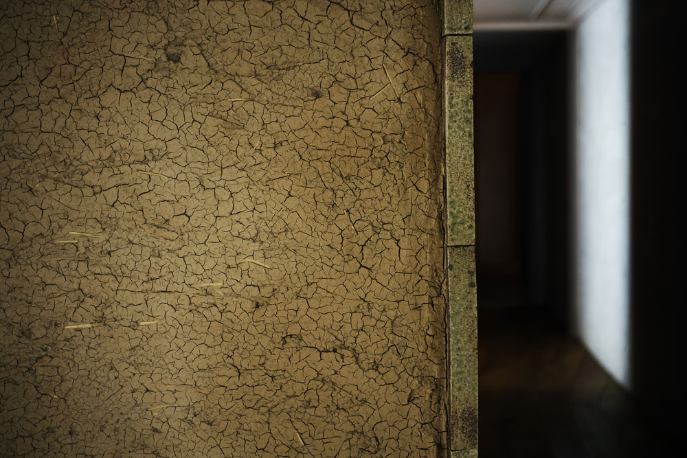 ひび割れが独特の質感を生み出す土壁は、廃屋となっていた蔵の建材を再利用したもの。