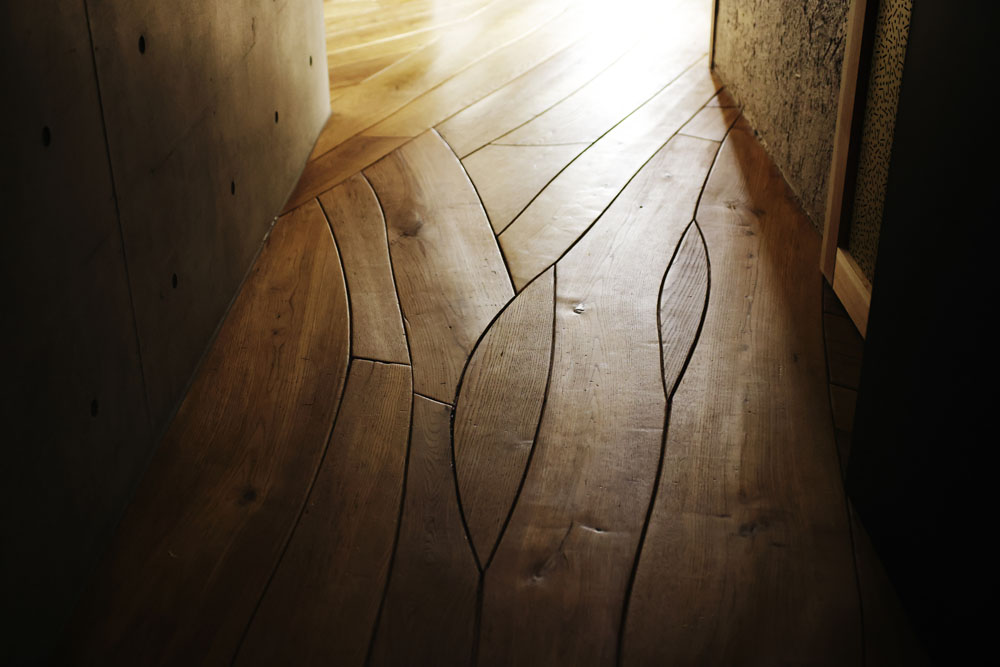 福井県のシンボルともいえる九頭竜川の流れをフローリングの寄木で表現。窓の外の海の眺めに向かって、流れを描くように設計されている。