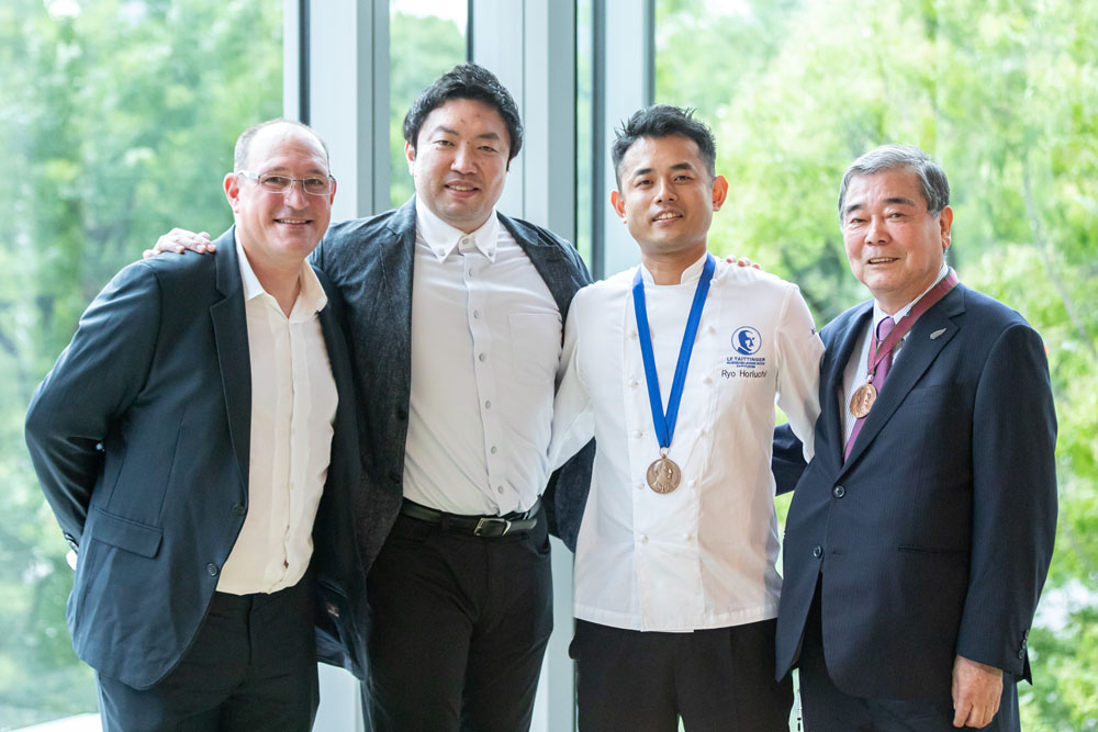 2022年７月19日、パレスホテル東京で開催された「第54回＜ル・テタンジェ賞＞国際シグネチャーキュイジーヌコンクール・アンテルナショナル」優勝祝賀パーティの一コマ。左からコンクールのアンバサダーで審査委員も務めるルノー・オージエ氏（トゥールダルジャン東京）、2018年コンクールの覇者、関谷健一朗シェフ（ガストロノミー　ジョエル・ロブション）、堀内亮シェフ（ル ジャルダン）、日本人初の1984年コンクール優勝者の堀田大シェフ。