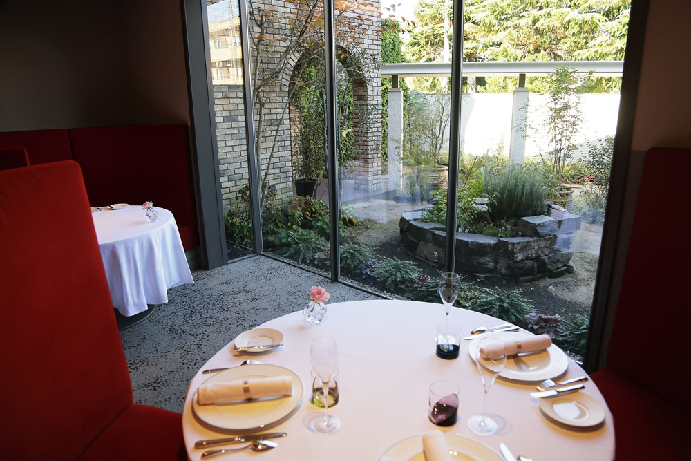 ハーブガーデンの中庭を望む「ル ジャルダン」の店内。蔦のからまる重厚な洋館の佇まい、広い空間にゆったりと配置されたテーブル、きらびやかなシャンデリアなど、古きよきメゾンの格調を感じさせる調度と洗練されたサービスが、心地よい時間の流れをつくり出す。