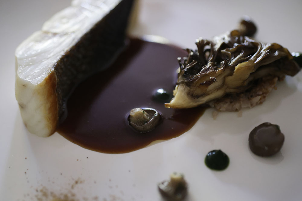 シンプルに焼いたスズキに、キノコの香り満載のガルニチュールとソースを添えて。「舞茸はローストするだけで驚くほどのおいしさ。キノコは総じて野趣が強く、風味も濃くて、創作心を刺激されます」と堀内シェフも太鼓判。