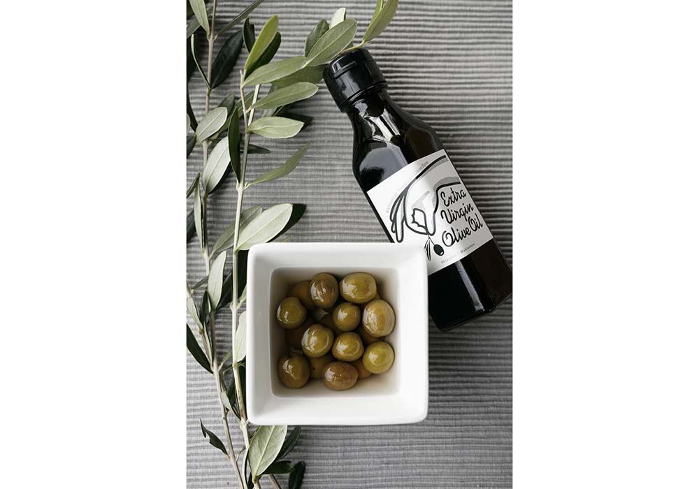 左から、生花市場に卸しているオリーブ若木の枝葉、オリーブ塩漬け、オリーブオイル。塩漬けはカリッとした食感の残った梅干しのよう。乳酸発酵の旨味も感じられる。2021年度から開封後でもオリーブオイルの酸化を防ぐ真空ボトルにリニューアル。より長い期間風味のよいオイルを楽しめるパッケージに。