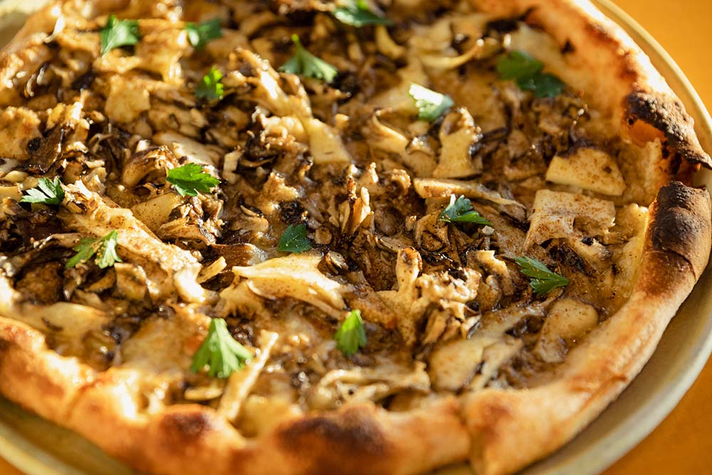 新潟県南魚沼市で栽培されている大黒舞茸をピッツァ１台に140g使い、赤牛のパルミジャーノチーズ（48カ月熟成）、モッツァレラ、プロボローネチーズなどと共に焼く。ピッツァ生地は、伊ピエモンテ州にある製粉会社「ムリーノ・マリーノ」の無農薬栽培小麦の石臼挽き全粒粉で作る。ダニエレシェフ愛用の粉だ。