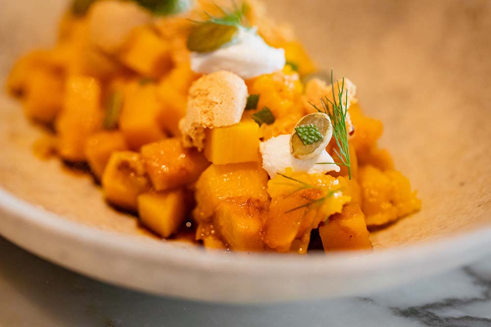 高知特産万次郎カボチャのサラダ。パンプキンオイルとバルサミコ酢で調味し、シェーブルチーズ、アマレッティをあしらう。万次郎カボチャは、nomaのポップアップではジュースに、INUAではカボチャ節にしてダシをとっていた。
