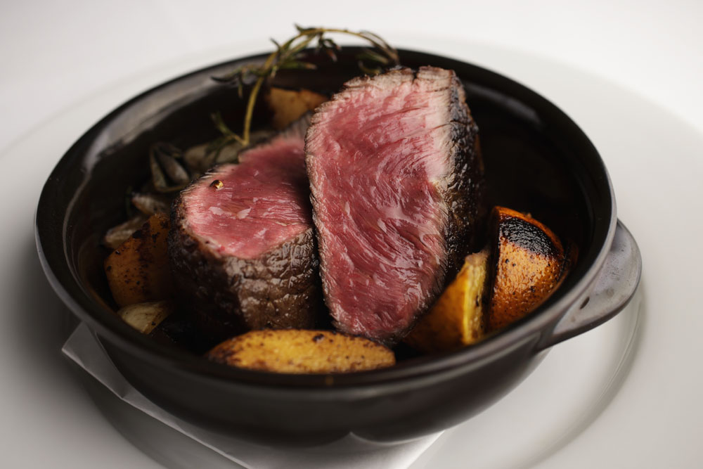 無角和種の香り焼き。トウガラシ（腕の部分）をタマネギ、カブ、ニンジンと共に、ハッサク、ローズマリー、セージ、ローリエ、バタックペッパー、ティムールペッパーなど香味素材と合わせて焼く。赤身の旨味がぐっと引き立つ。