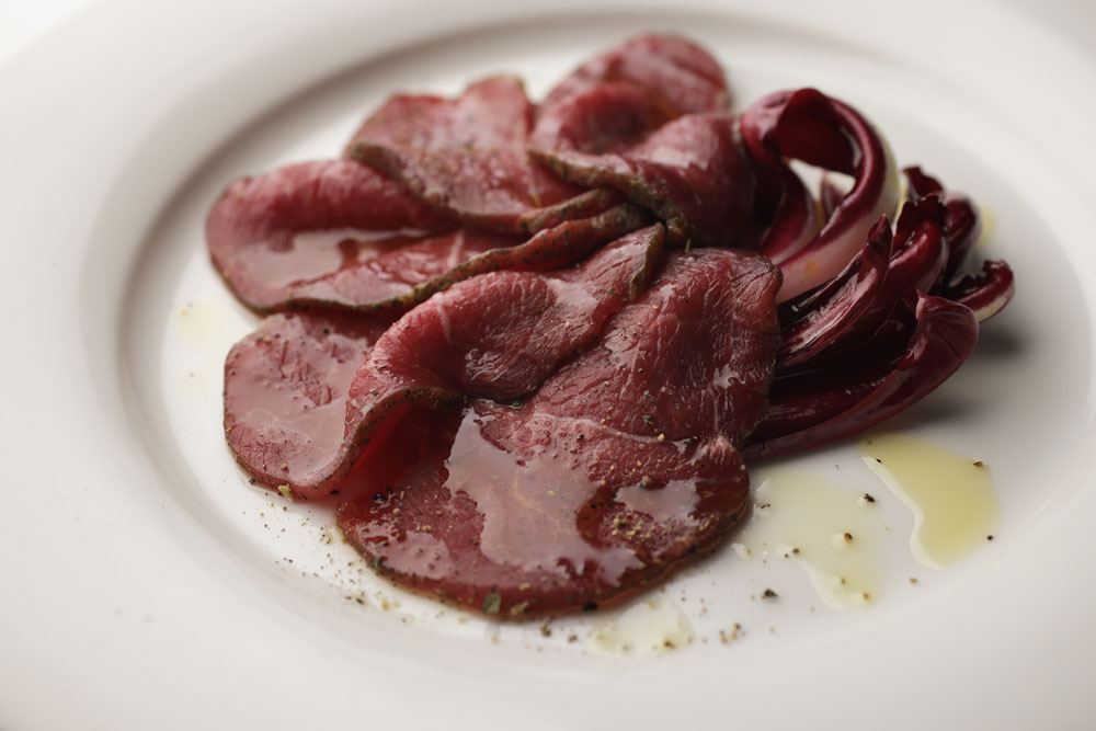 無角和種のカルネ・サラータ。部位は同じくトウガラシ。塩と香辛料に漬け込んで薄切りに。トレヴィーゾを添え、オリーブオイルとコショウをかけて。テクスチャーは滑らか、驚くほど上品な味わい。