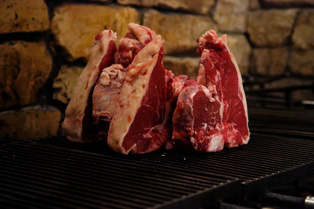 Ｔボーンの炭火焼き。塩をして１時間ほど置いた後、骨の部分を下にして網の上に立たせ、骨から火を入れていく。