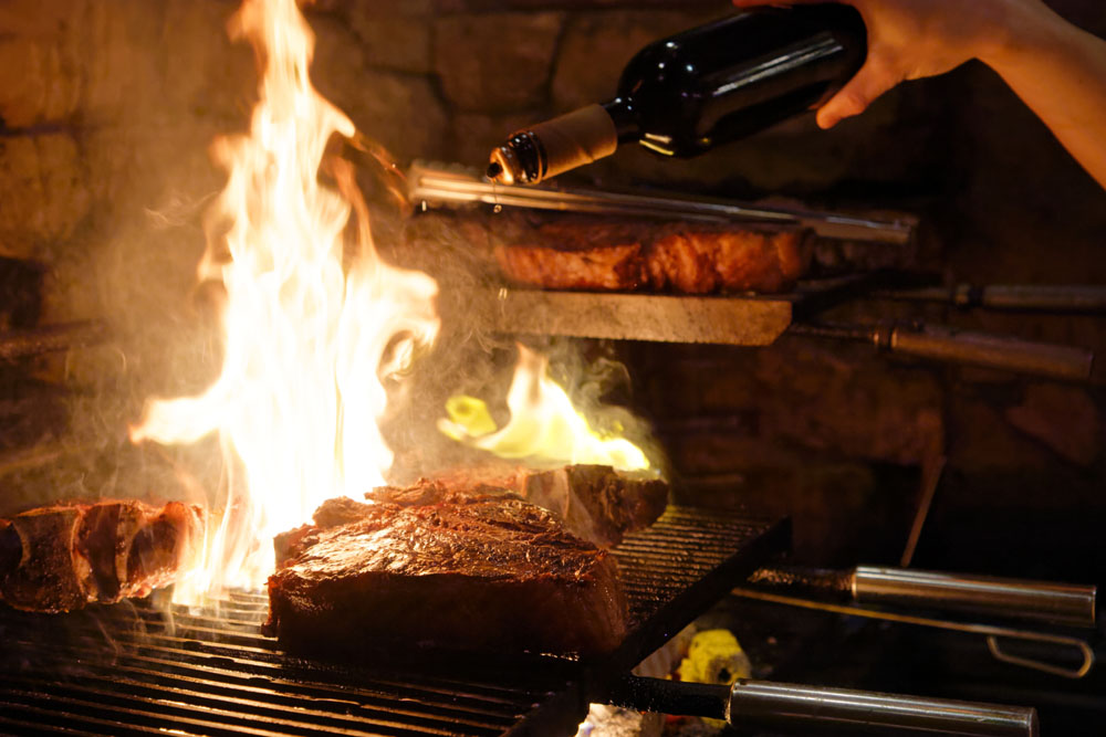 仕上げにオリーブオイルをかけて炎を立たせ、肉の表面を香ばしく焦がす。