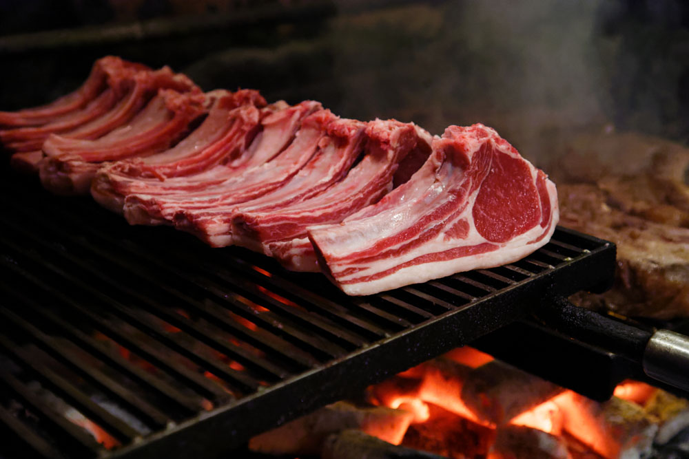 骨付きロースラムの炭火焼き。ビーフ同様、塩をして１時間ほど置いた後、骨を下にして焼き始める。