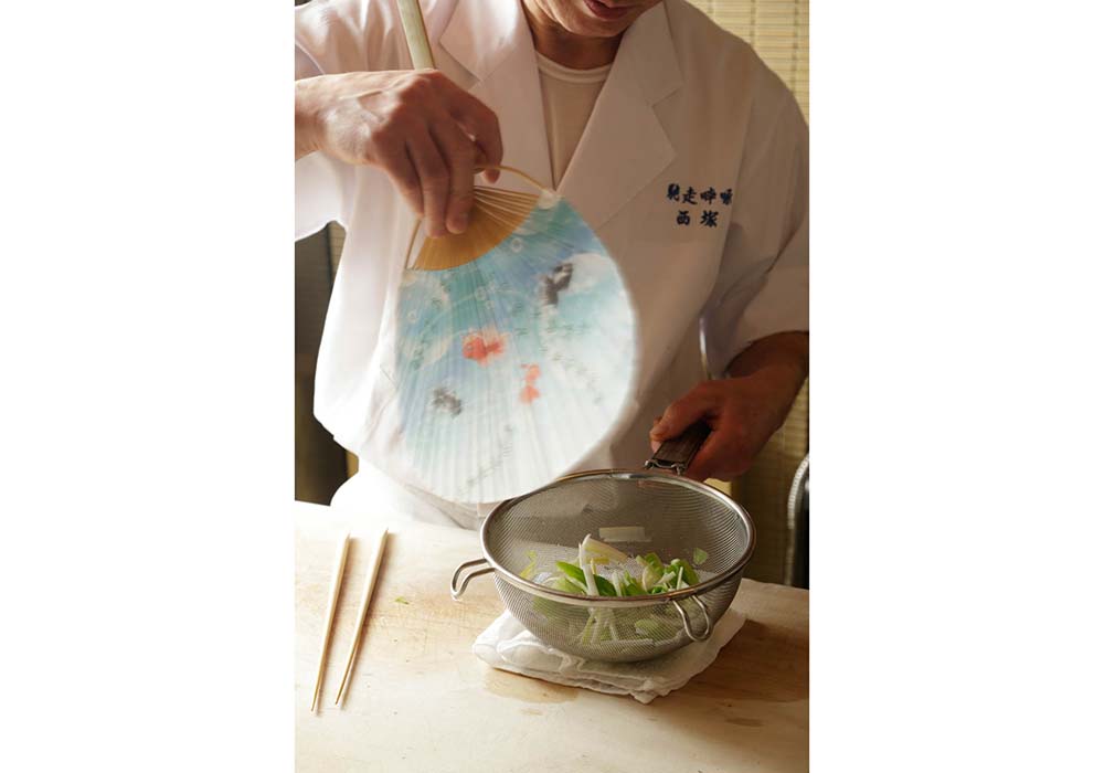 ザルに上げ、うちわであおぎ冷ます。 POINT：水にさらさず、あおいで冷ますことでウルイの風味、食感を保つ。