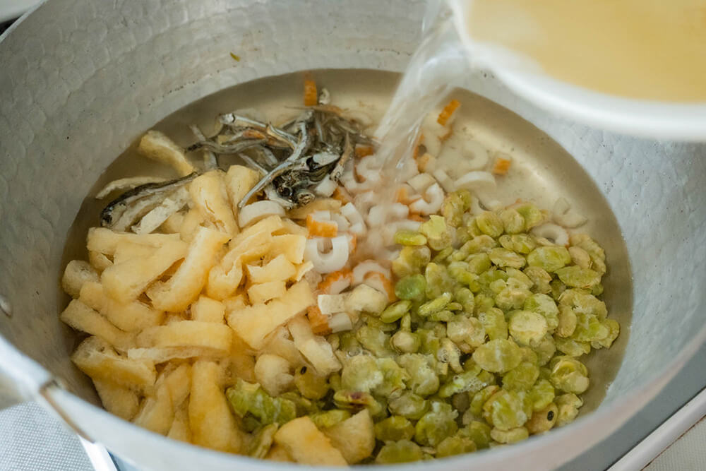 鍋に打ち豆、油揚げ、ちくわ、煮干しを入れ、だし汁を加える