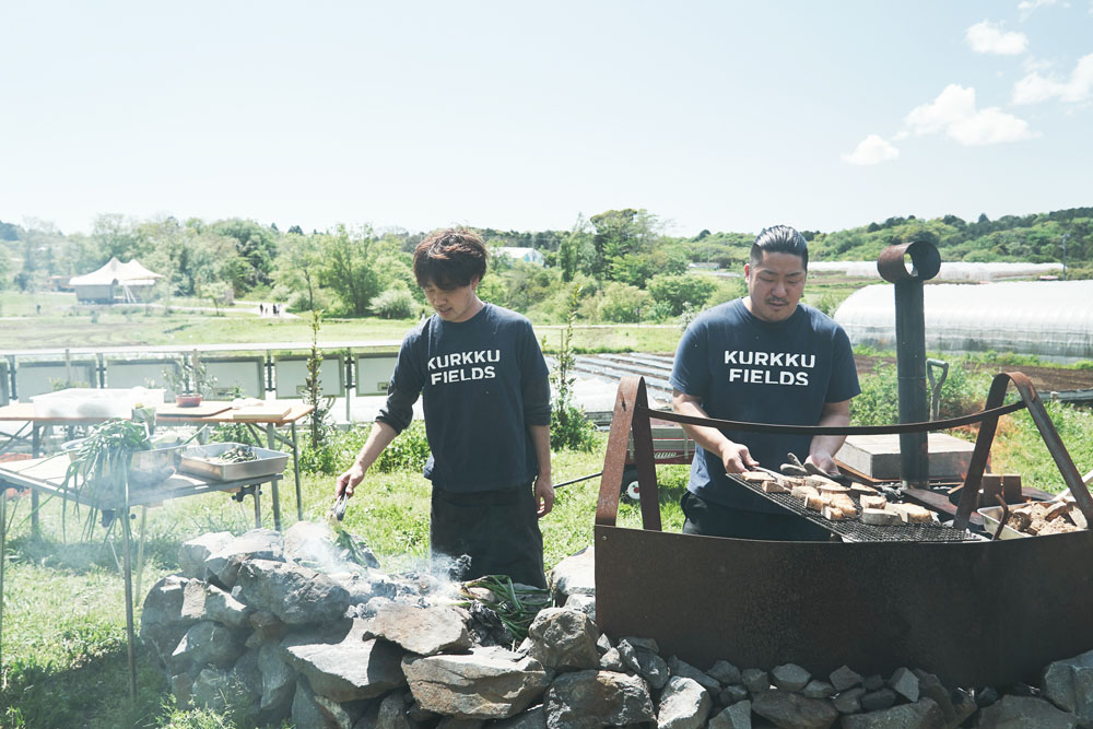 山名新貴シェフ（左）とドリンク担当の小高光さん。鹿肉のほかにも、みんなが収穫した葉タマネギを焼いたり、パンを炙ったり。ちなみにパンは場内で採れた小麦や千葉県産の小麦をブレンドした全粒粉のカンパーニュ。