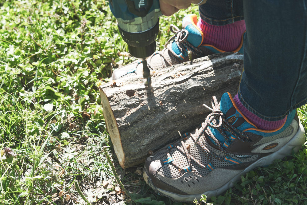 廃材のコナラの幹に電動ドリルで穴を開けていく。開ける場所に法則はなく、「作る人のセンスが出ますね」と剛さんは言います。