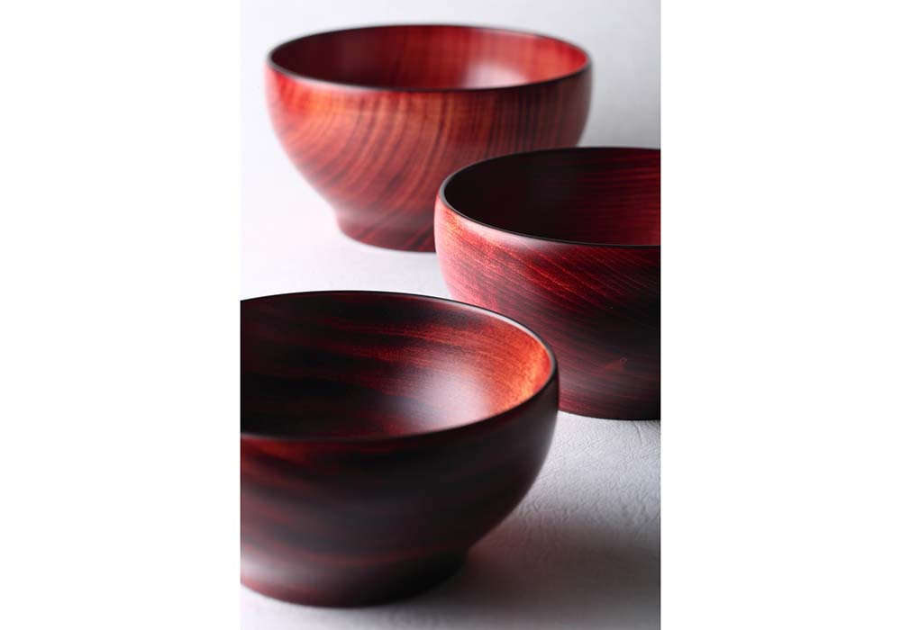 漆器「めぐる」には、拭き漆と呼ばれる技法で仕上げたバージョンも。下地をせずに木地に透明の漆を直接摺り込むため、木目を生かしたナチュラルな風合が備わる。
