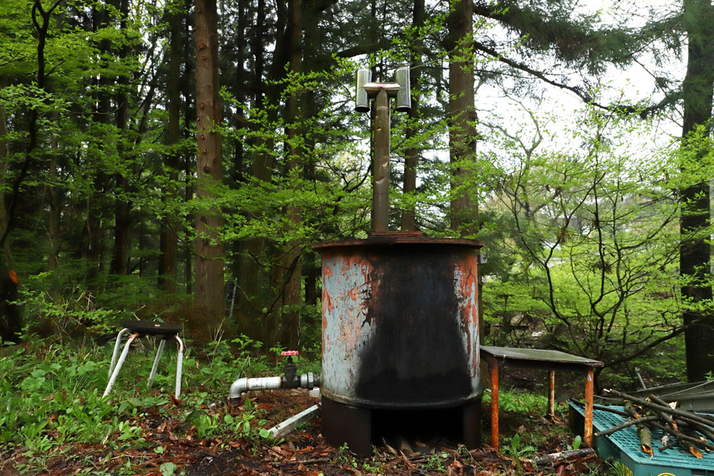 丸太小屋の周りには、キャンプ場、宿泊小屋、憩いの小屋など、セルフビルドの活動施設が立つ。写真の五右衛門風呂は、スキー場のリフトの柱の再利用。