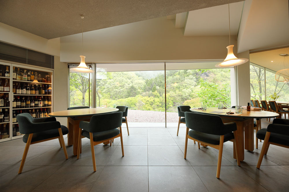 ダイニングの窓からは、川を挟んだ向こう岸の山の緑が美しいグラデーションを見せる。敷地の横を利根川支流の薄根川が流れ、水音が聞こえてくる。