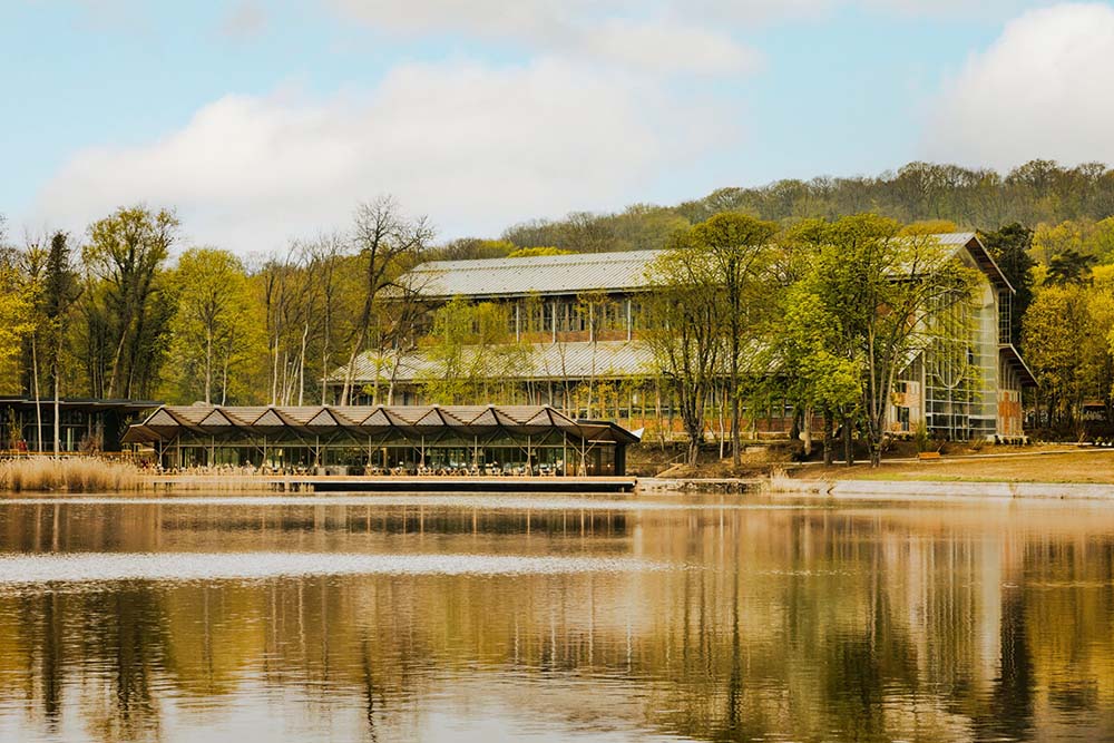 （写真）人工池に面したレストランは全200席。木目調の自然で落ち着いた内装で温かみがある。サービスは気取りがなく、リラックスした接客が好感を持てる。
