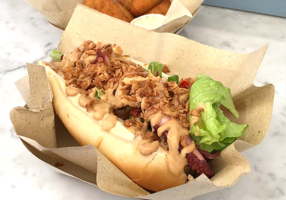 （写真）「タコのパニーノ（pane e polipo）」（10ユーロ）は、ヴィンコットで甘味をつけたBBQマヨネーズ、野菜の酢漬け、フライドオニオンがアクセントに。