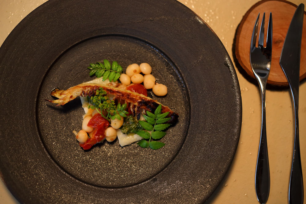 薪火グリルで炙り焼きにしたタケノコ、白インゲン豆、ドライトマト、山椒のペーストで構成したひと皿。