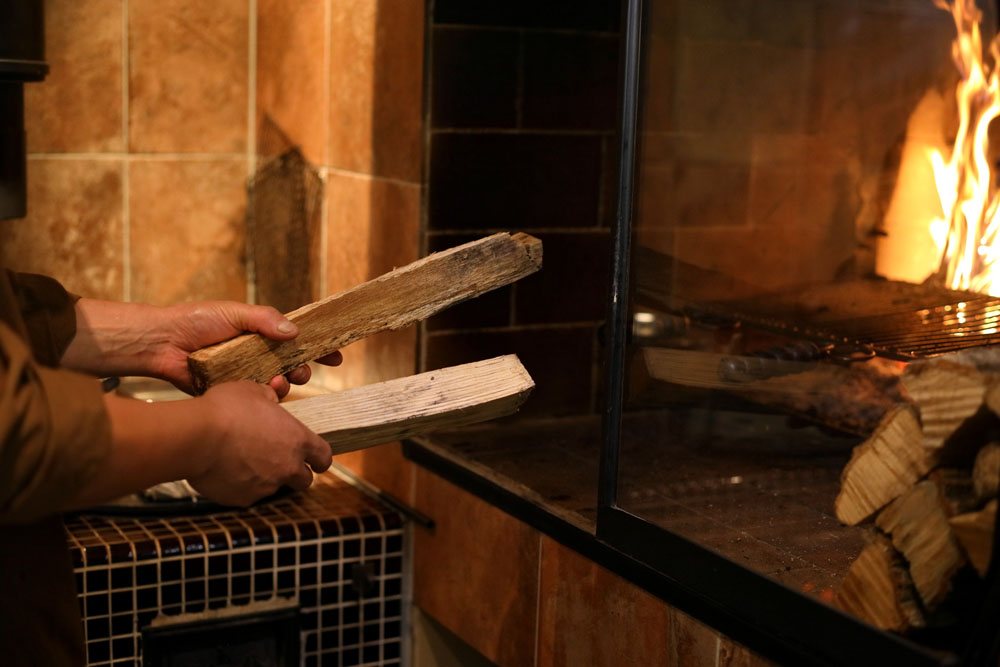 薪火グリルの奥の薪は絶えず継ぎ足して火を絶やさない。