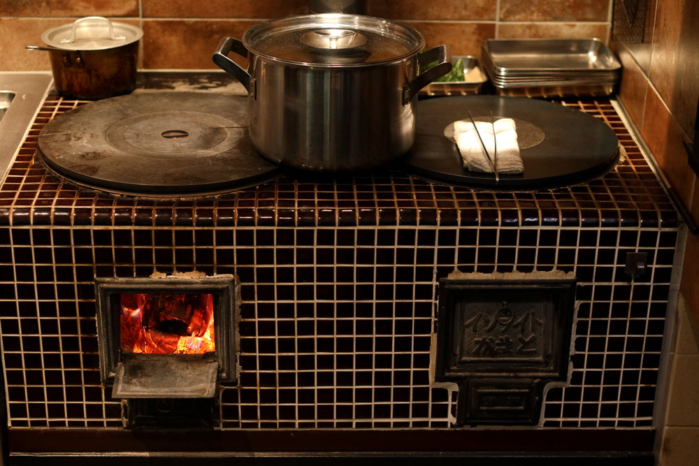 「ヴェンティノーヴェ」の厨房に導入された薪焚かまど。「単式（ひと口）もあるんですよ。２連式にしたけれど、思いのほか火力が強いので、ほぼひと口しか使わない」