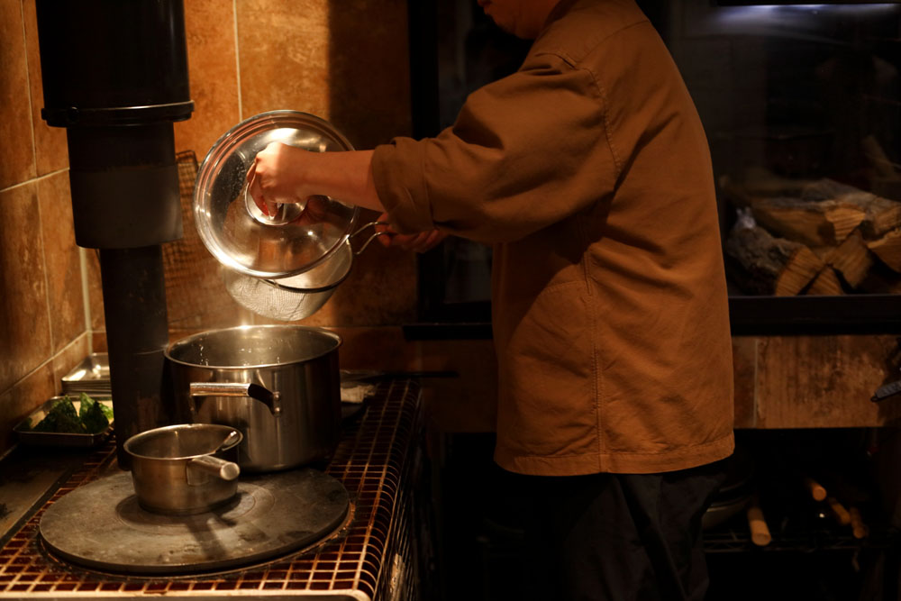 かまどの真ん中はパスタを茹でる寸胴鍋の定位置。放熱しにくい構造なので、沸きが早い。写真左手に見える煙突がとても重要。「かまどより煙突のほうが遥かに高価（笑）」