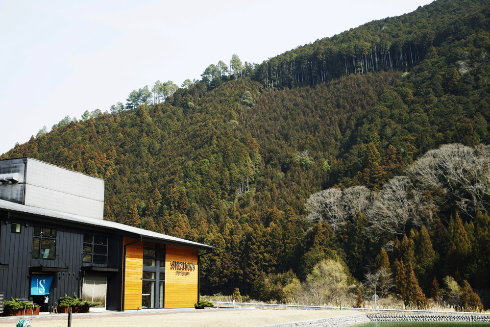 静岡市街から車で約40分。山間の針葉樹林を背景に佇む「ガイアフロー静岡蒸溜所」。