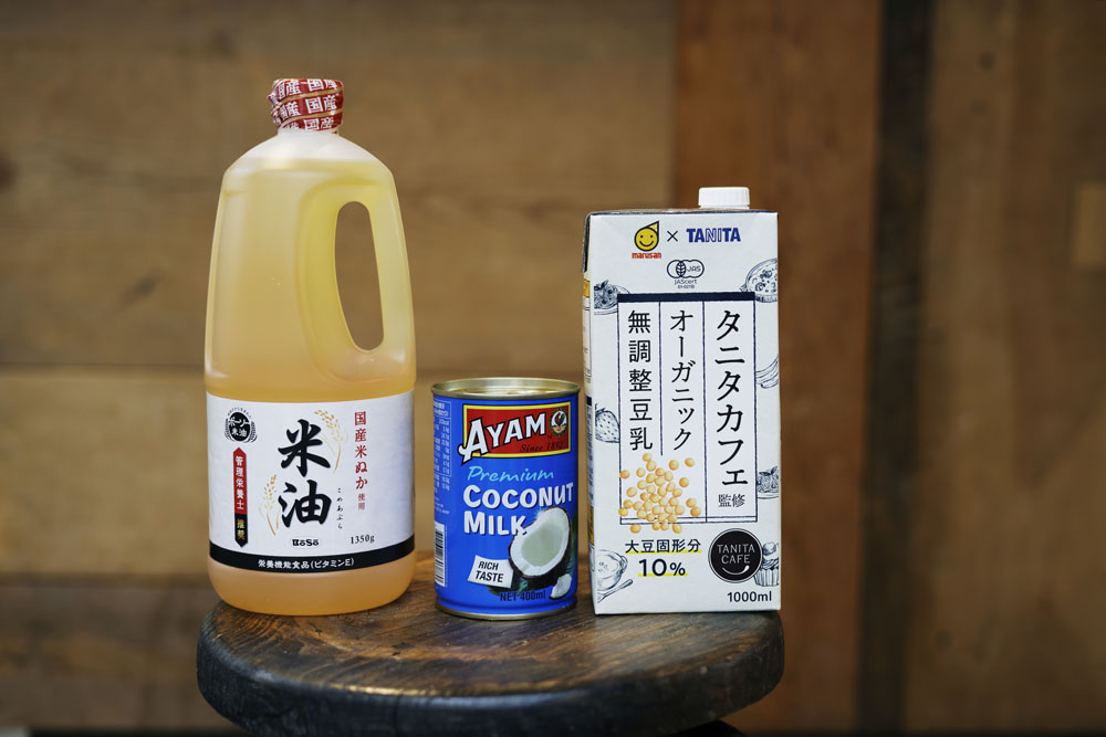 （左から）国産の米ぬかから作られた「ボーソー」の米油はドーナッツや食パン、菓子パンなどに使用。「すっきりした味で、２日目も油臭くならない」。ドーナッツ生地の風味づけと固形油脂の役割でも使うココナッツミルク。オールドファッションドーナッツや菓子パン生地に使用する豆乳。