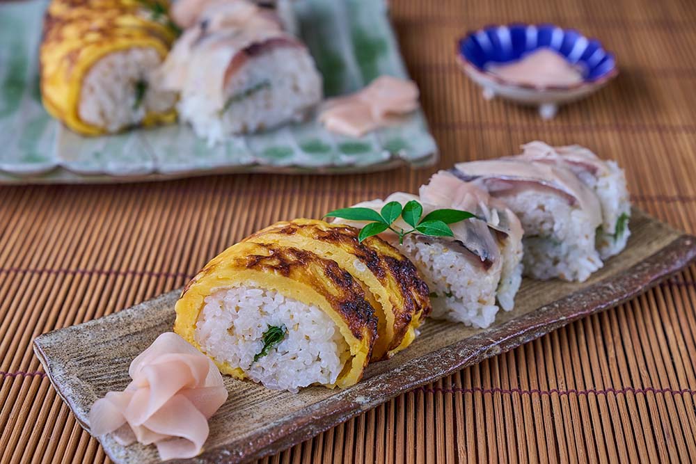 松崎さんお手製の鯖寿司と卵寿司。鯖を浸したゆず酢は、魚肉成分が溶け出して酸味がまろやかになる。松崎さんは、これを濾して冷蔵し、すし飯や酢の物などに再利用。ゆず酢100%を使ったすし飯は、強い酸味を程よくするため、砂糖の量を増やして調整。おいしいすし飯のコツは、熱いご飯にゆず酢をまんべんなく混ぜ、扇風機でパーっと冷やすこと。熱いご飯が冷める時に酢を吸い、その後表面の水を風で飛ばすと、ゆずの風味がほのかに香る口当たりの良いご飯になる。