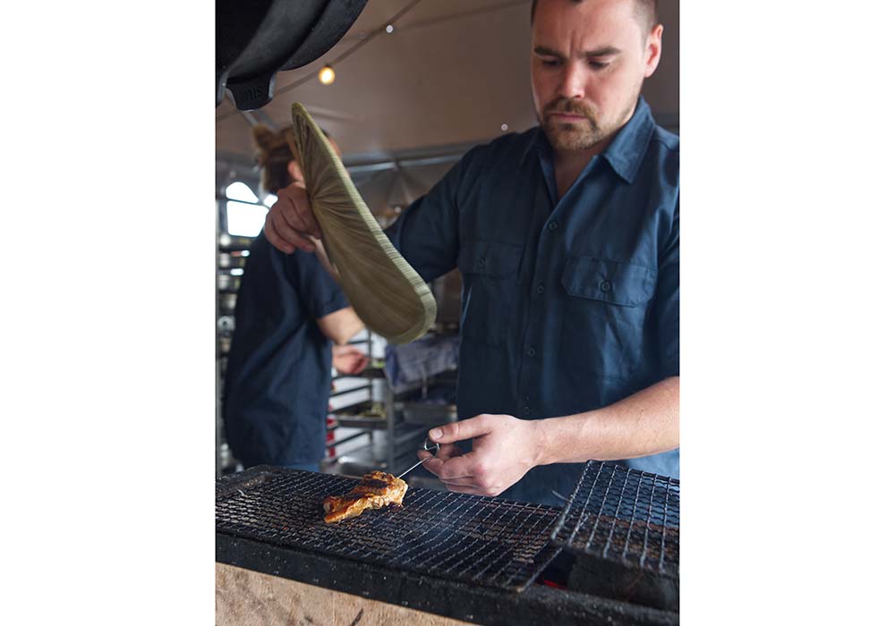 （写真）シェフのトビアス・ベックは29歳。日本から持ち帰った炭火コンロに炭を入れて団扇であおげば、香ばしい香りが客席まで漂ってくる。