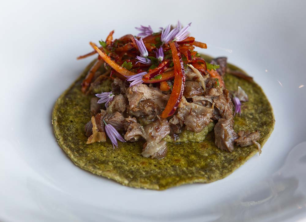 （写真）ラムのタコス。オイルマリネした仔羊肉を、薪の香りを纏わせながらゆっくり火を入れてほぐし、スパイシーなチャツネや歯応えを残したパプリカと共に焼きたてのトルティーヤにのせた。