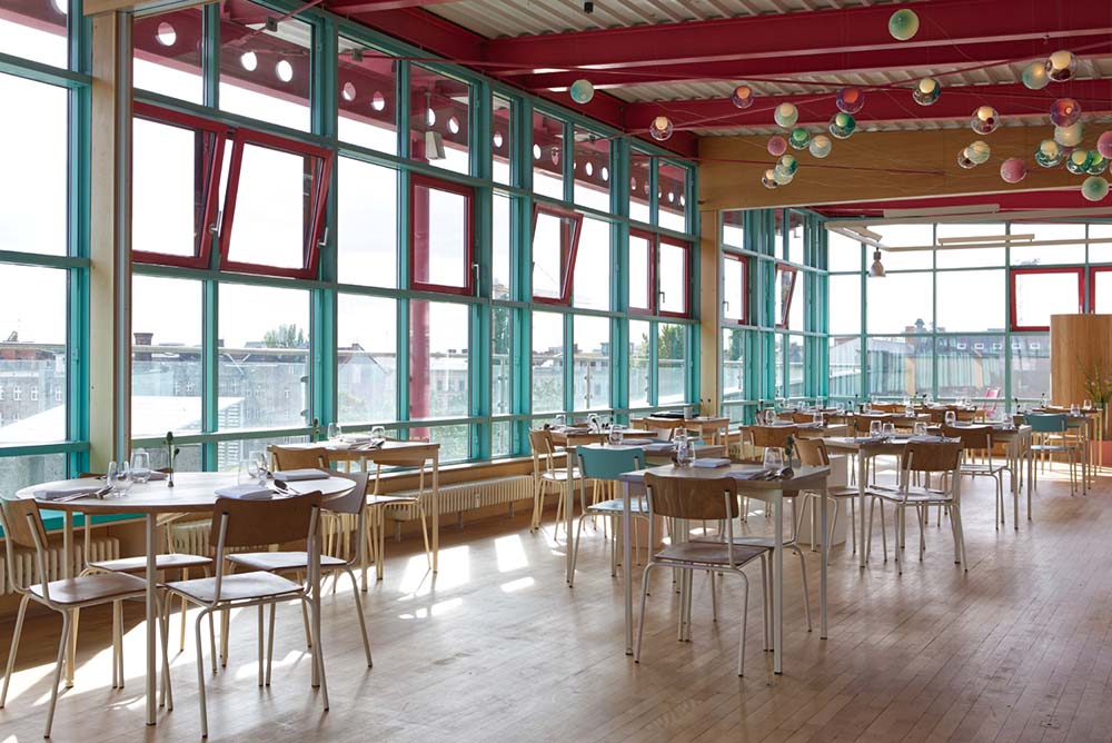 （写真）教室を思わせる簡素なスツールとテーブルを並べて客席に。手前のテラスにテントを張ってキッチンにしている。