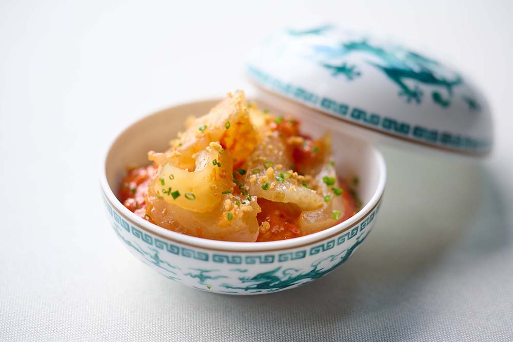（写真）「発酵唐辛子と魚の浮袋のご飯（剁椒花膠飯）」。12年物の魚肚をイベリコ豚の脂で炒め、自家製発酵唐辛子で調味。炊きたての新潟産コシヒカリにのせ、イベリコ豚の肉をクランチ状にしてトッピングして提供する。酸味と辛味、凝縮した旨味が楽しめるシェフのシグネチャー料理だ。