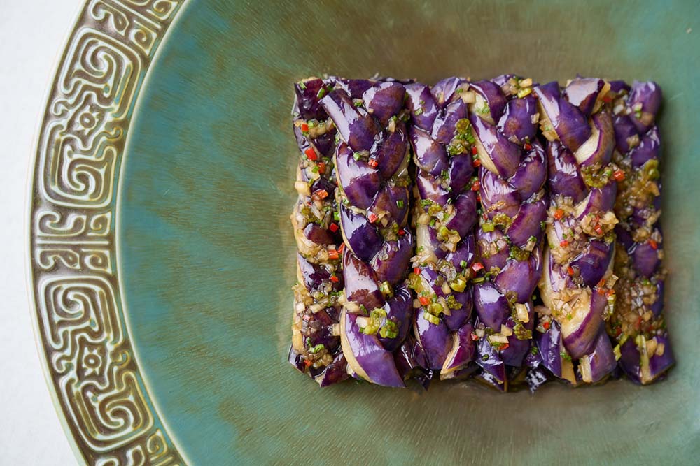 （写真）「ナスと自家製サワーソース（煙燻酸汁茄子）」。中国の家庭でよく使うナスをガストロノミーの一皿に。芸術的な職人技で編み込み、酸味のある自家製ソースに漬け込んだ。さらにリンゴのスモークチップで香ばしい燻香をまとわせている。