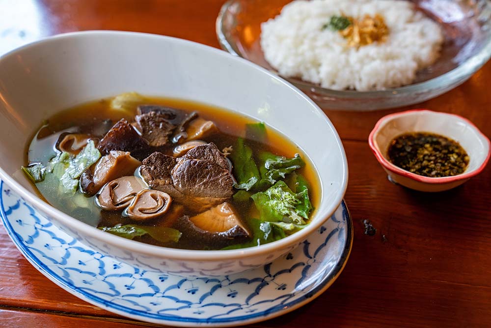 店のスペシャリテ、「バクテーバビ」（単品￥950・セット￥1150・ともに税込）。アルカリイオン水とニンニク・甘草・八角・桂皮・丁子を合わせて３時間弱火で煮た後、豚肩ロースを加えて１時間、さらに自家製“特殊”調味料を加えて４時間煮る。体に染みわたる深くクリアな味わいは、膝の手術で入院した妻・捷子さんへの差し入れにも重宝した。「看護師さんたちに羨ましがられました」